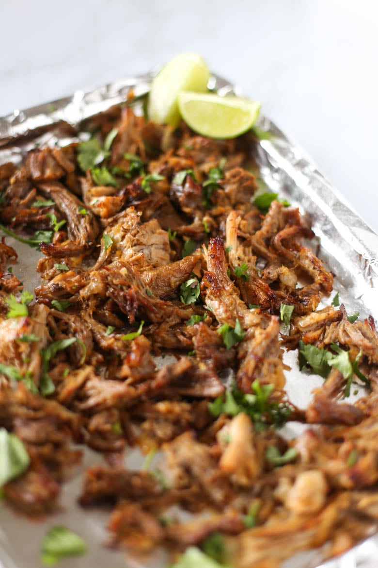 Instant Pot carnitas on a foil-lined baking sheet with chopped cilantro on top.