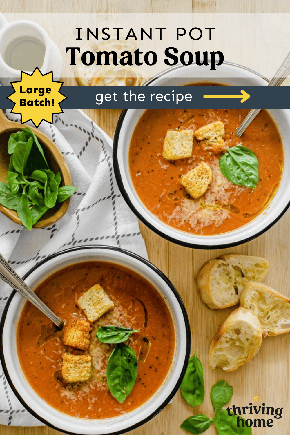 Two bowls of tomato soup with croutons and fresh basil leaves on top.