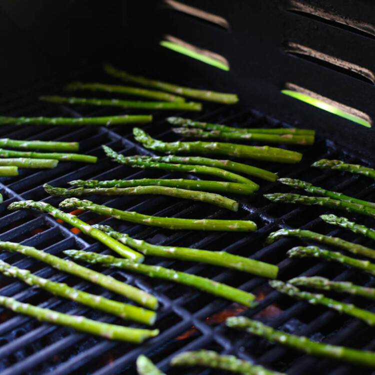 A grill with asparagus on the grate.