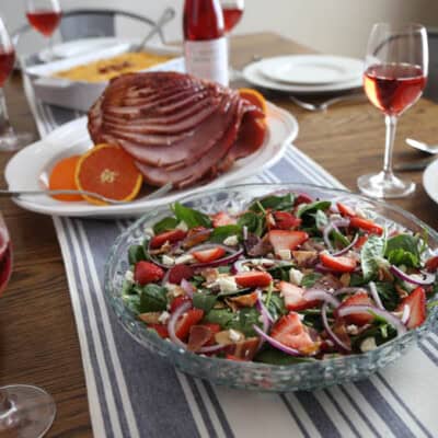 Easter lunch on table with salad, ham, hash brown casserole, and wine