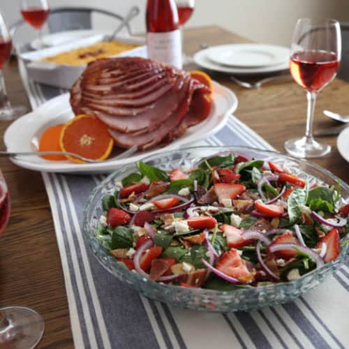 Easter lunch on table with salad, ham, hash brown casserole, and wine