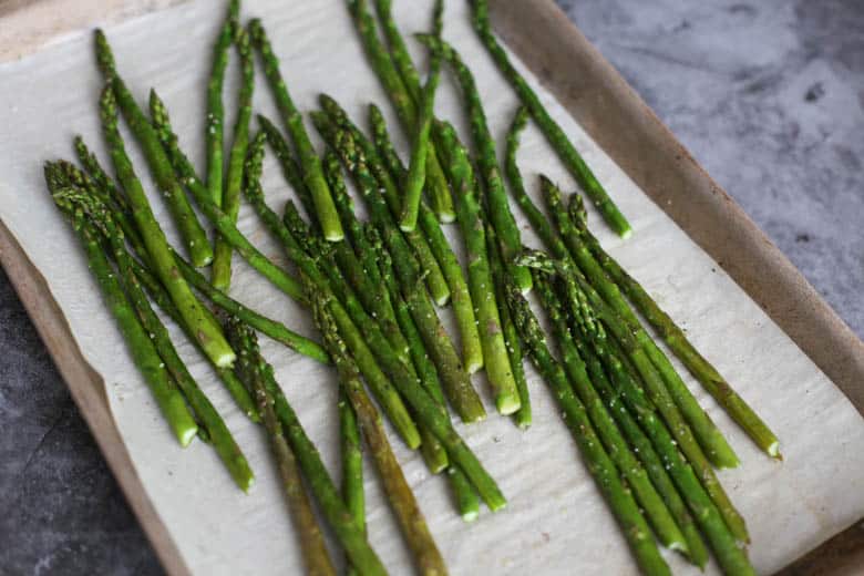 Roasted asparagus on a baking sheet lined with parchment paper.