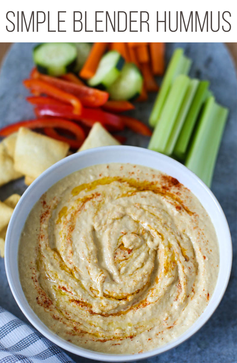 Homemade hummus in a bowl with raw veggies and pita chips surrounding it.
