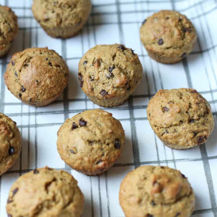 Banana chocolate chip muffins lined up on a kitchen towel.