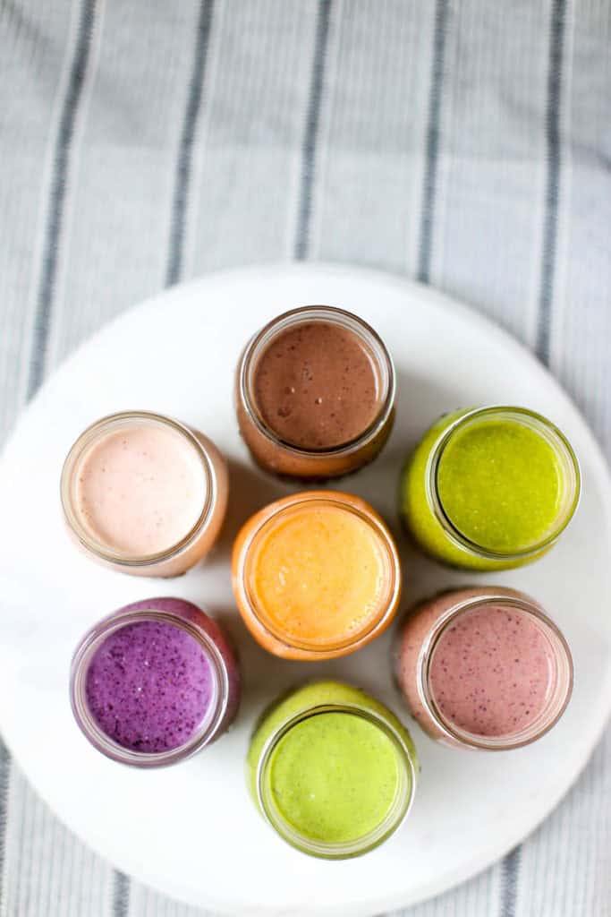 overhead shot of 7 different smoothies in mason jars