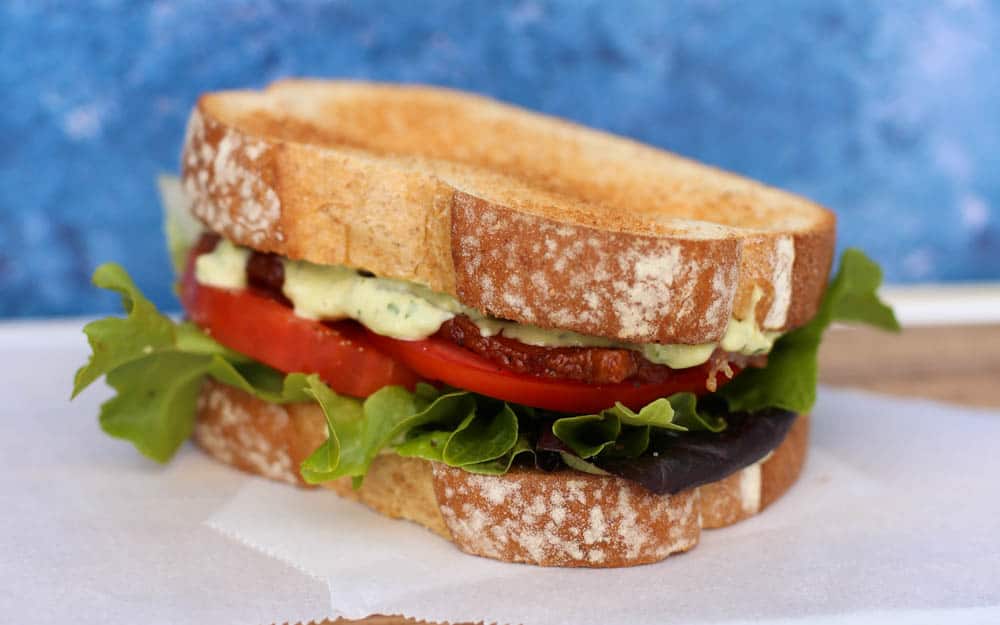 Bacon, lettuce, tomato sandwich with avocado aioli on thick artisan bread slices.