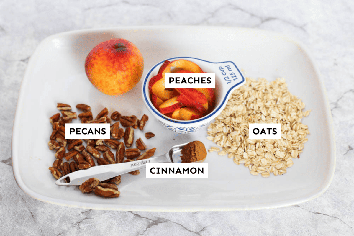 Peach cobbler overnight oats ingredients measured out on a white platter and labeled.
