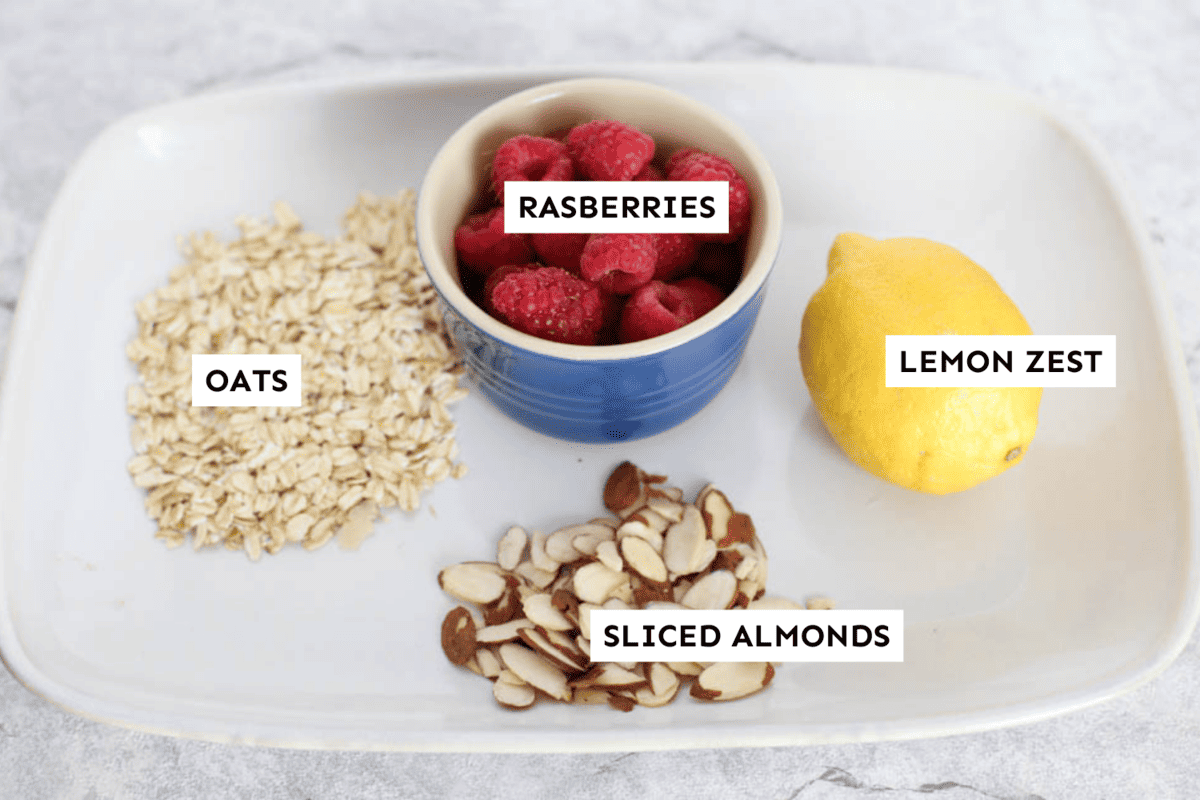 Raspberry overnight oats ingredients measured out on a white platter and labeled.