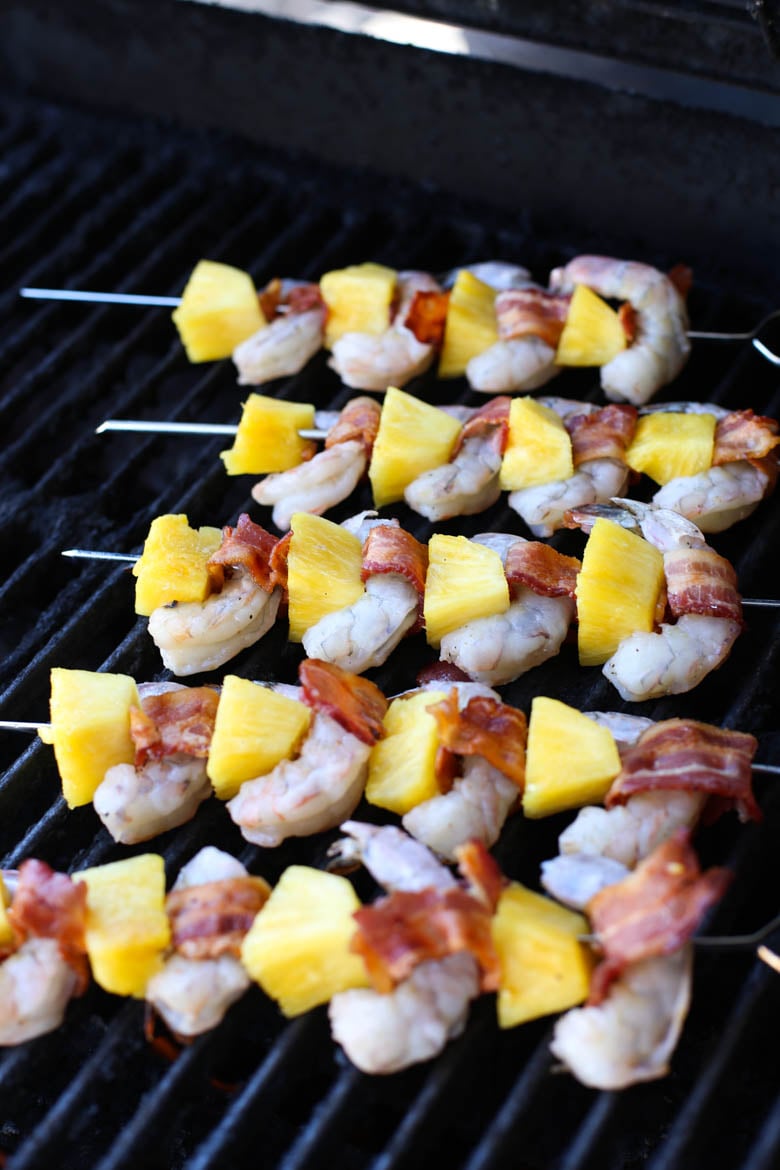 Bacon-wrapped shrimp and pineapple kabobs on a grill.