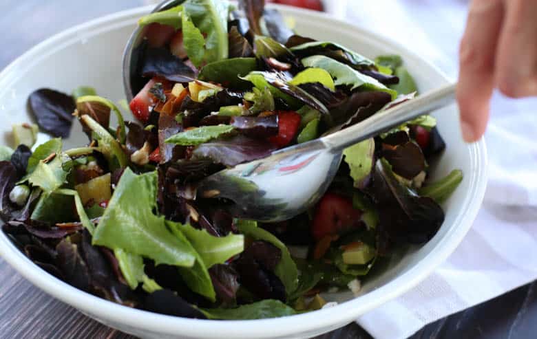 Strawberry avocado salad being tossed