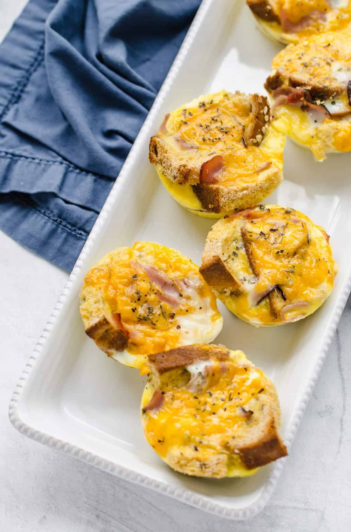 Breakfast casserole muffins lined up on a narrow rectangular serving platter.