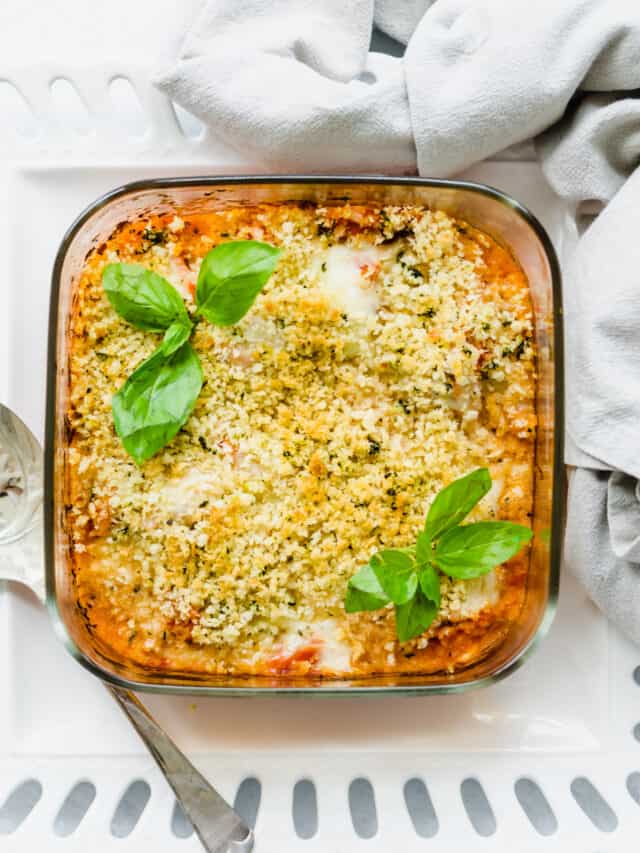 Chicken parmesan casserole in a glass baking dish with basil leaves on top.
