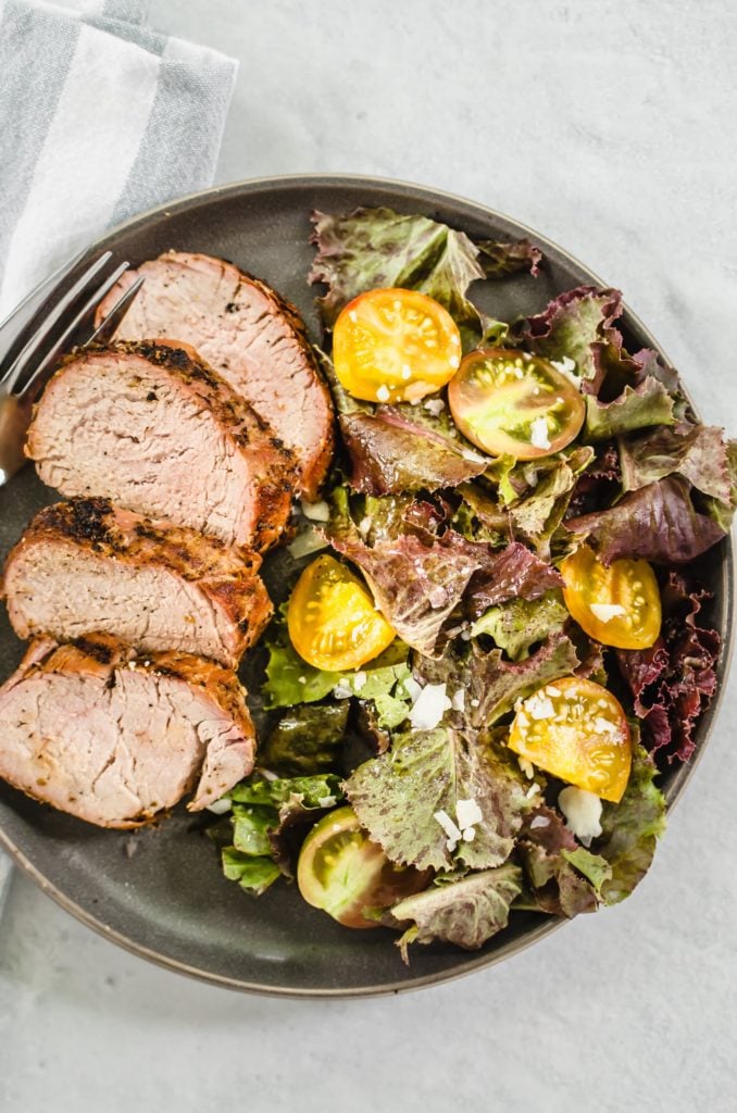 Grilled pork tenderloin on a plate with salad