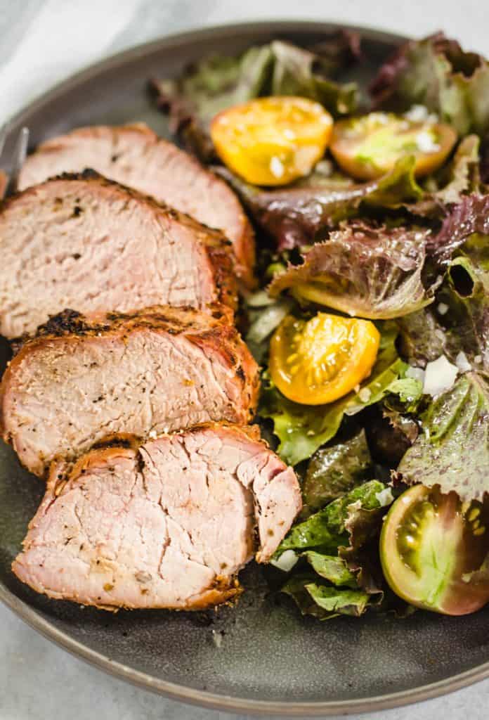 Grilled pork tenderloin on a plate with salad