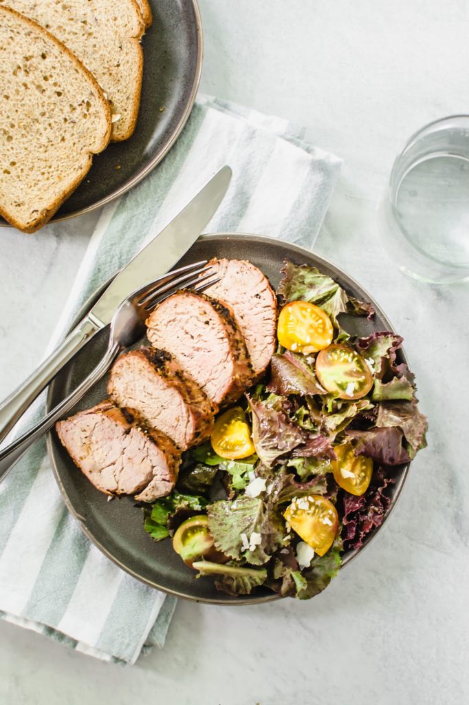 Cooked pork tenderloin on a plate with salad 