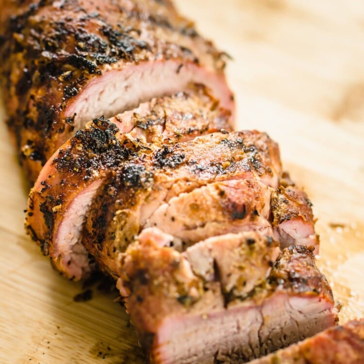 Pork tenderloin sliced and on a cutting board.