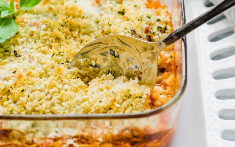 chicken parmesan casserole in a glass baking dish with a spoon