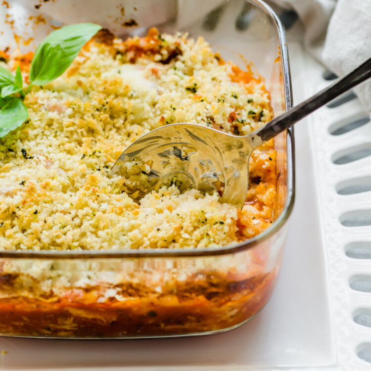 Chicken Parmesan casserole in a glass baking dish with a spoon.