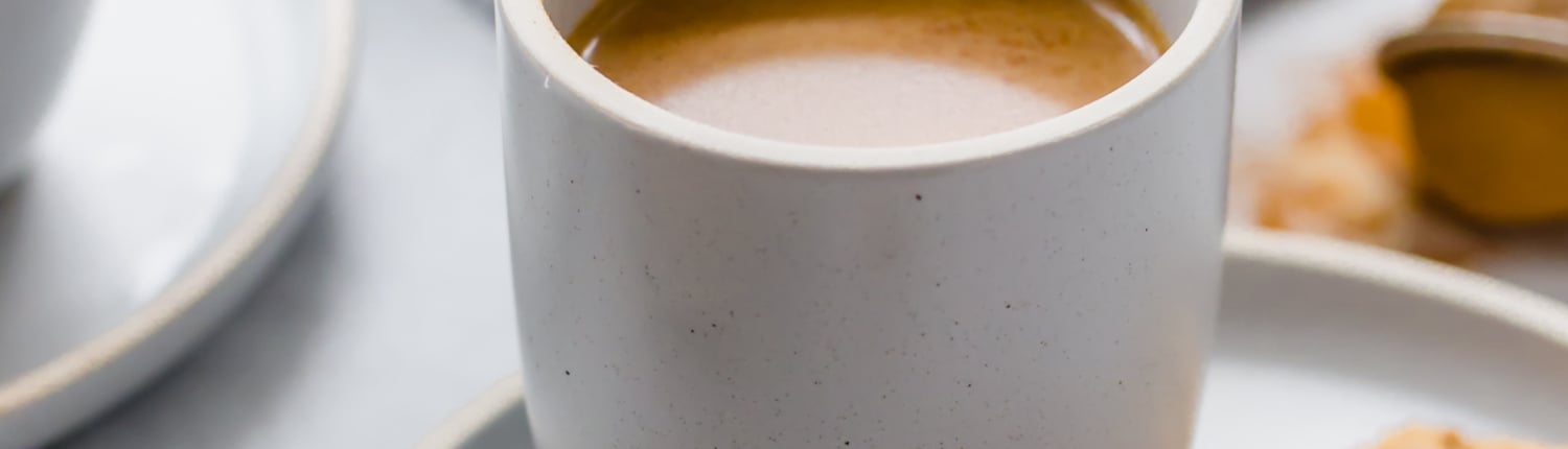 Pumpkin spice latte in a mug with two snickerdoodle cookies on a plate next to it.