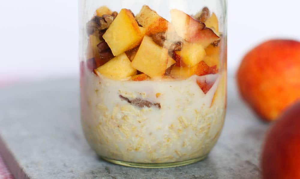 Overnights Oats with milk, oats, flax, peaches, cinnamon, vanilla, and pecans in a mason jar.