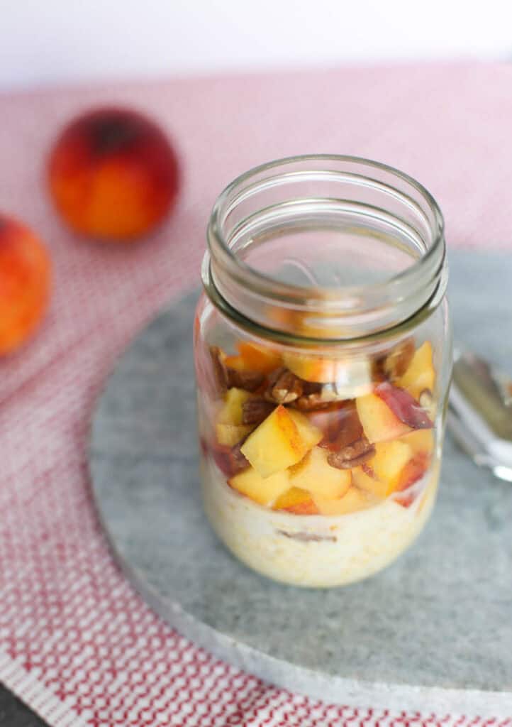 Overnights Oats with milk, oats, flax, peaches, cinnamon, vanilla, and pecans in a mason jar.