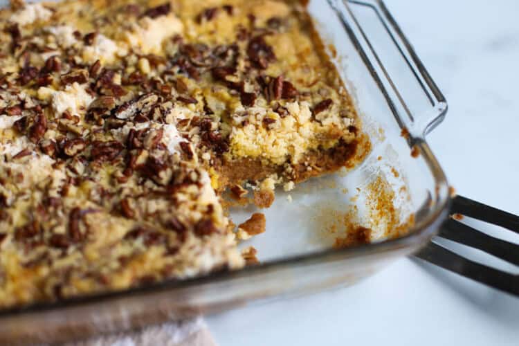 Pumpkin dump cake in a casserole dish with a piece missing.