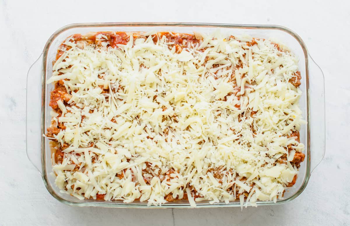 Shredded mozzarella spread across baked pasta. 