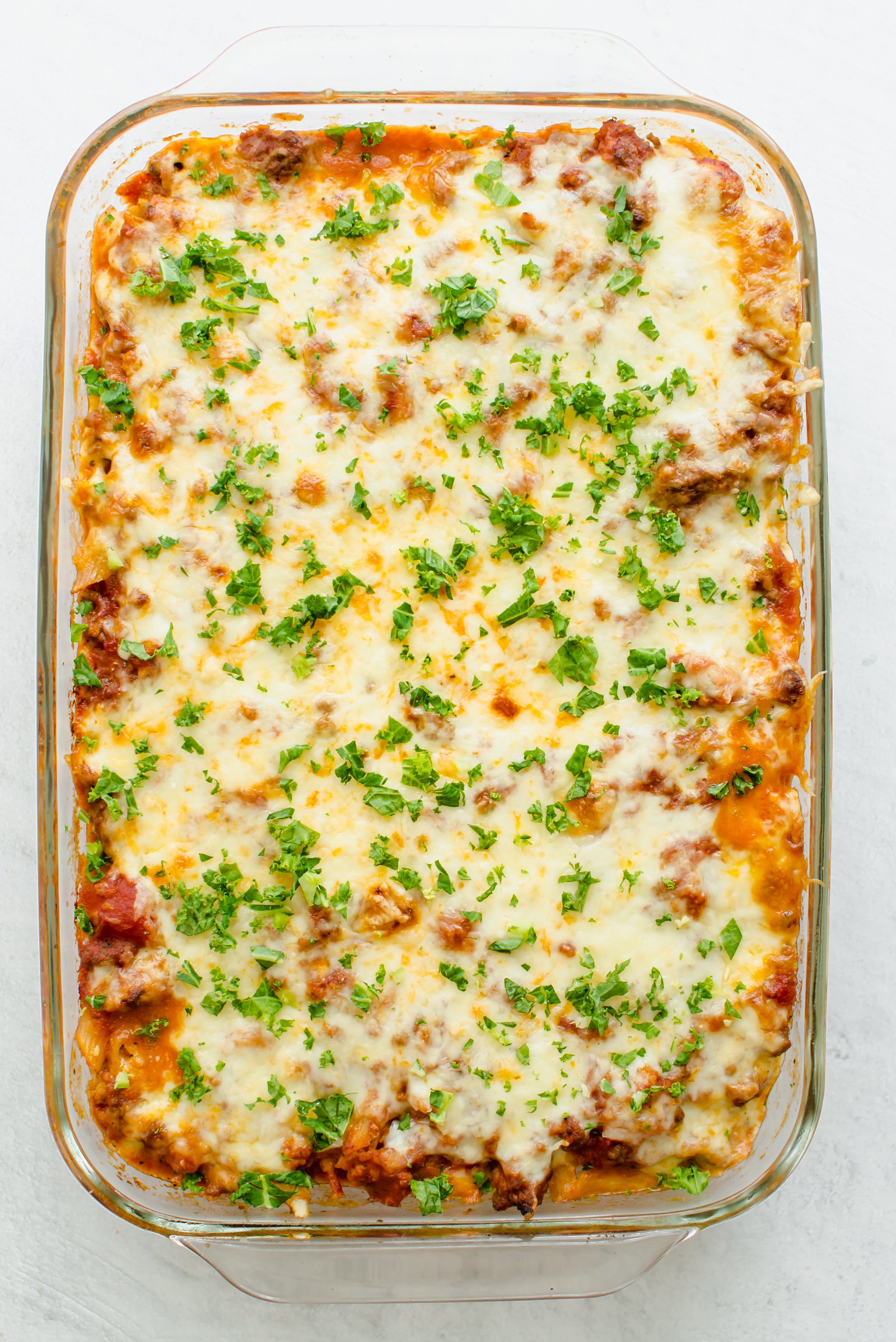Glass 9x12 pan with baked penne pasta ready to serve.