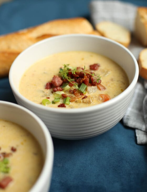 Slow Cooker bacon and cheddar potato soup served in white bowls with toppings.