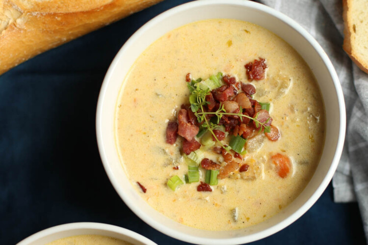 Bowl of cheddar and bacon potato soup with crusty bread on the side.
