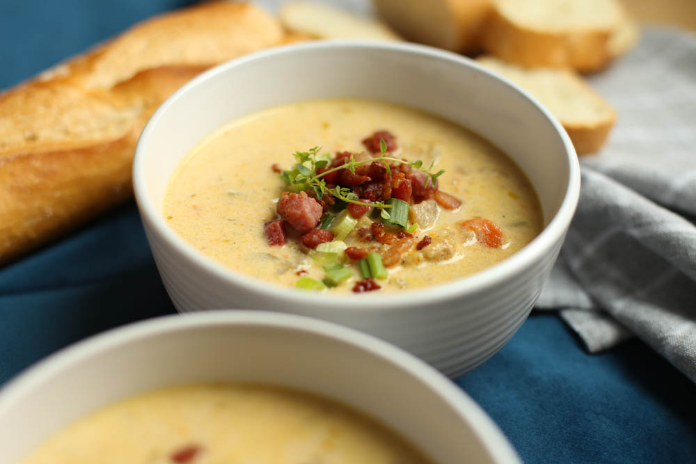 Slow Cooker Cheddar and Bacon Potato Soup in white bowls with bread.