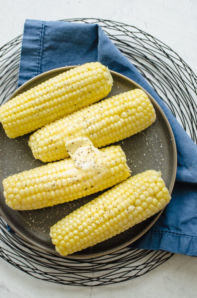 Microwaved corn on a gray plate with butter