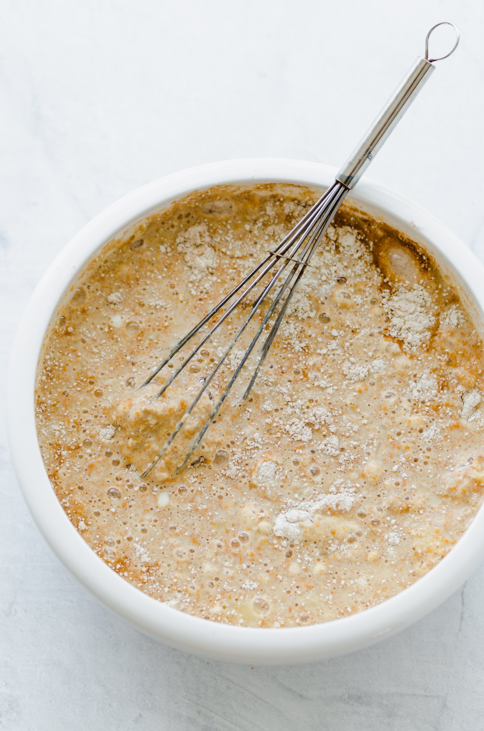 Pumpkin pancake batter in a bowl with whisk.