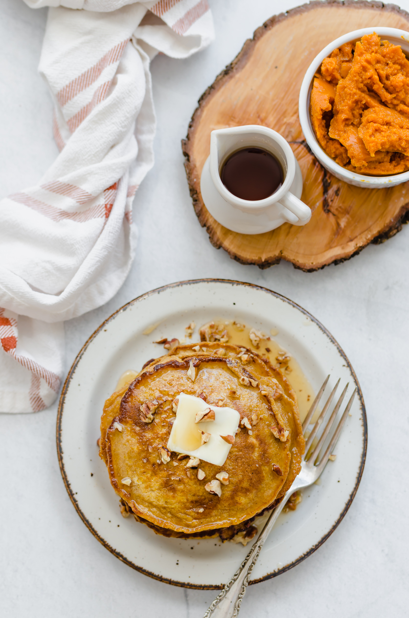 Pumpkin pancakes on a plate with butter on top.