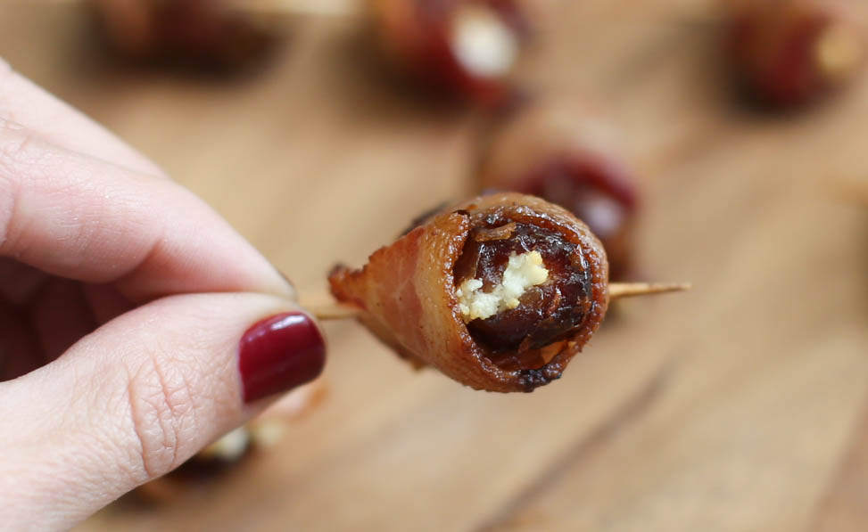 Bacon-Wrapped Dates with Goat Cheese on a cutting board