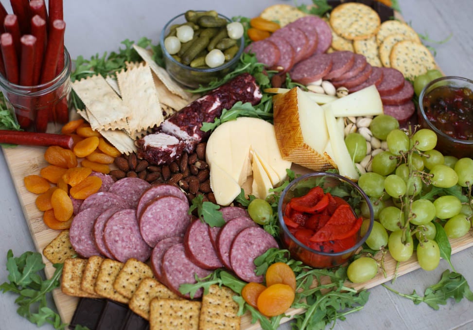 A simple charcuterie board with meat, cheese, crackers, fruit, and more.
