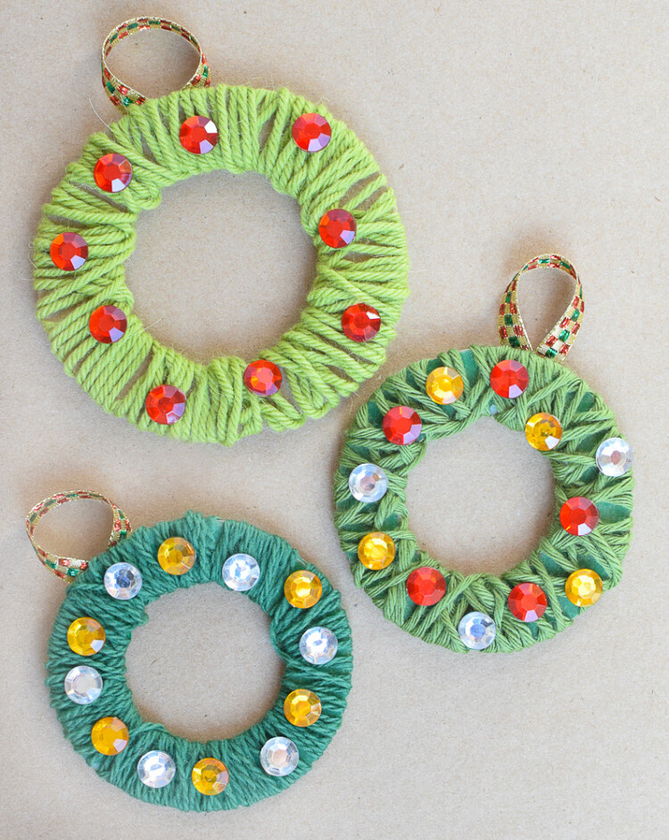 Wreath shaped cardboard wrapped in different color green yarns and sequin ornaments.