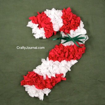 Tissue paper candy cane craft made of crumpled red and white tissue paper glued on to a candy can shape cutout.