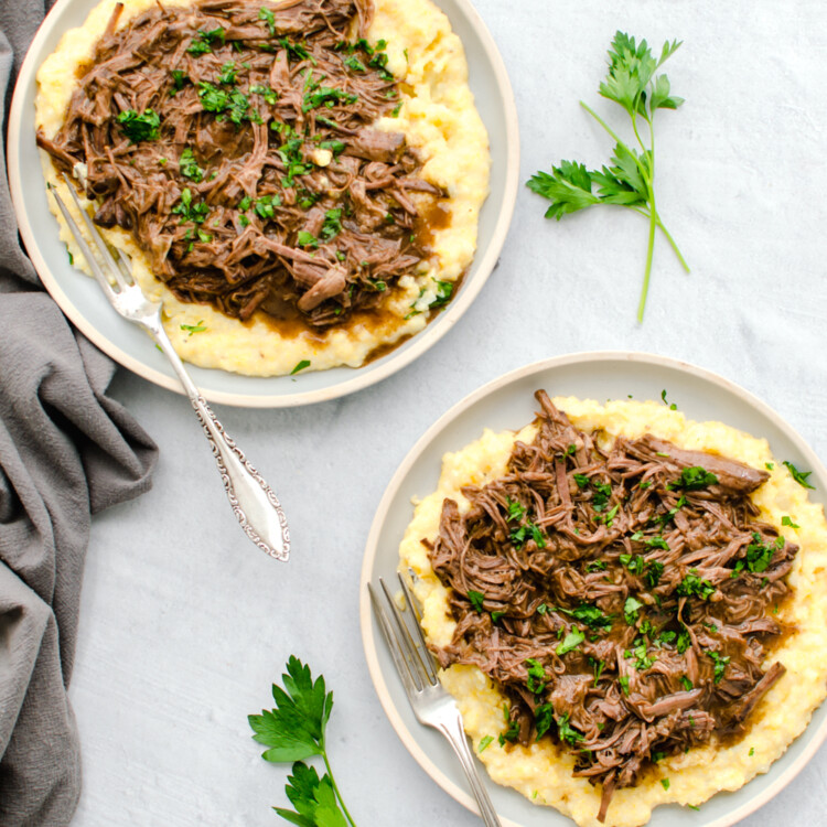 Balsamic shredded beef on top of polenta on a plate.