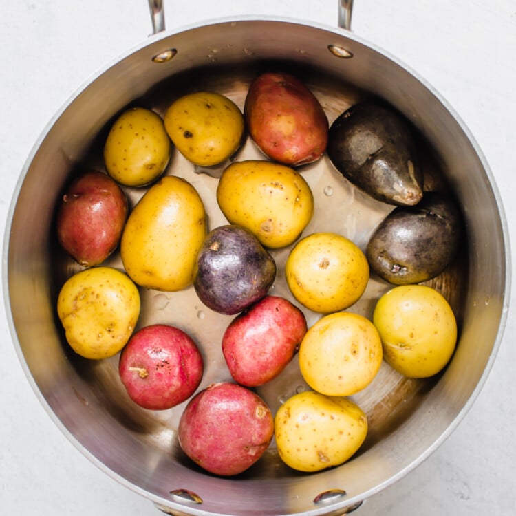 Red, blue, and yellow washed baby potatoes in a pot.