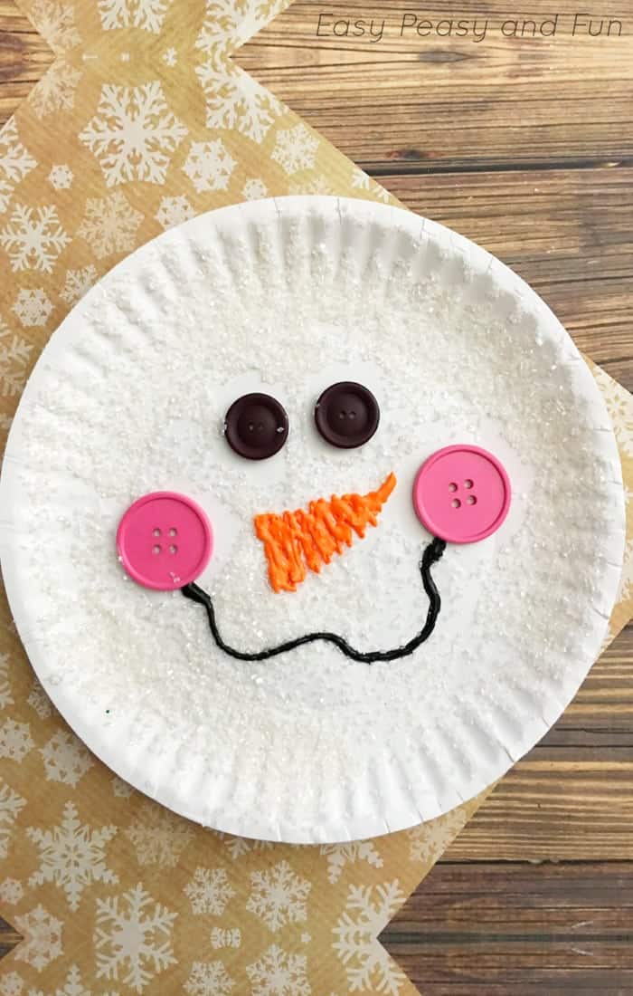 Paper plate snowman with button eyes and cheeks, and a black pipe cleaner for its mouth.