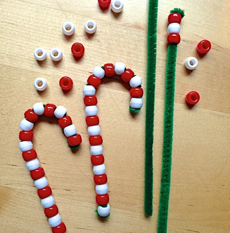 Two bead candy canes finished with green pipe cleaners and red and white beads next to them.