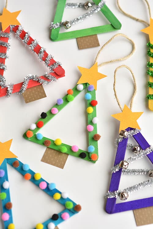 Popsicle sticks glued into a triangle shape, painted and then decorated with pipe cleaners, small jingle bells, and pom poms to look like Christmas trees.
