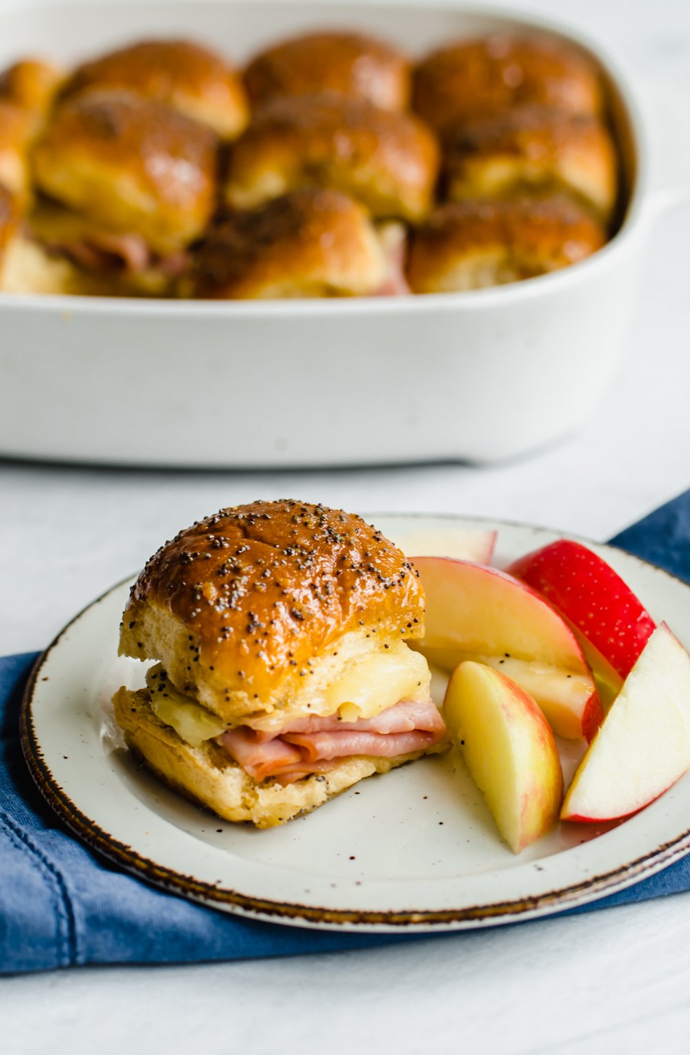 Ham & Cheese slider on a plate with apples.