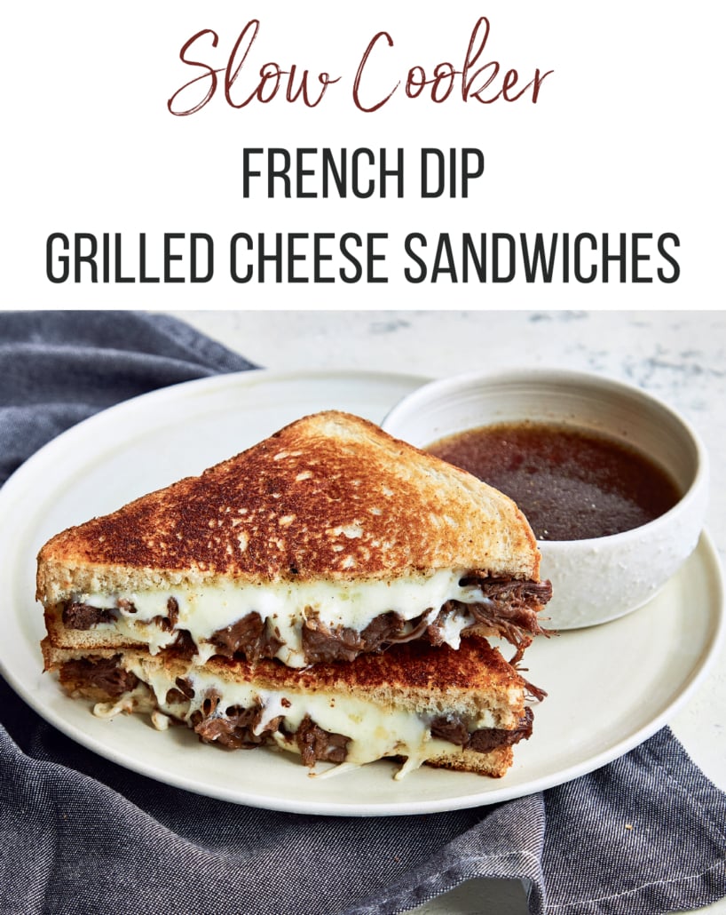 French Dip Grilled Cheese Sandwiches made in the slow cooker. Sandwich on a white plate with a small bowl of au jus next to it.
