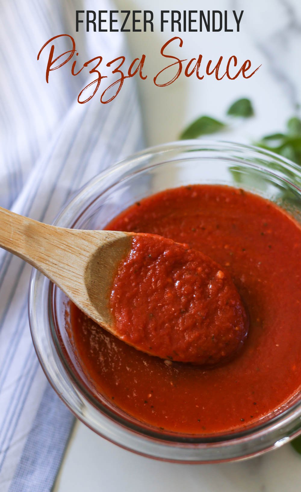 Freezer-friendly sugar-free pizza sauce in a glass bowl with wooden spoon.
