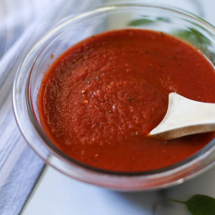 Bowl of homemade pizza sauce with a wooden spoon in it.