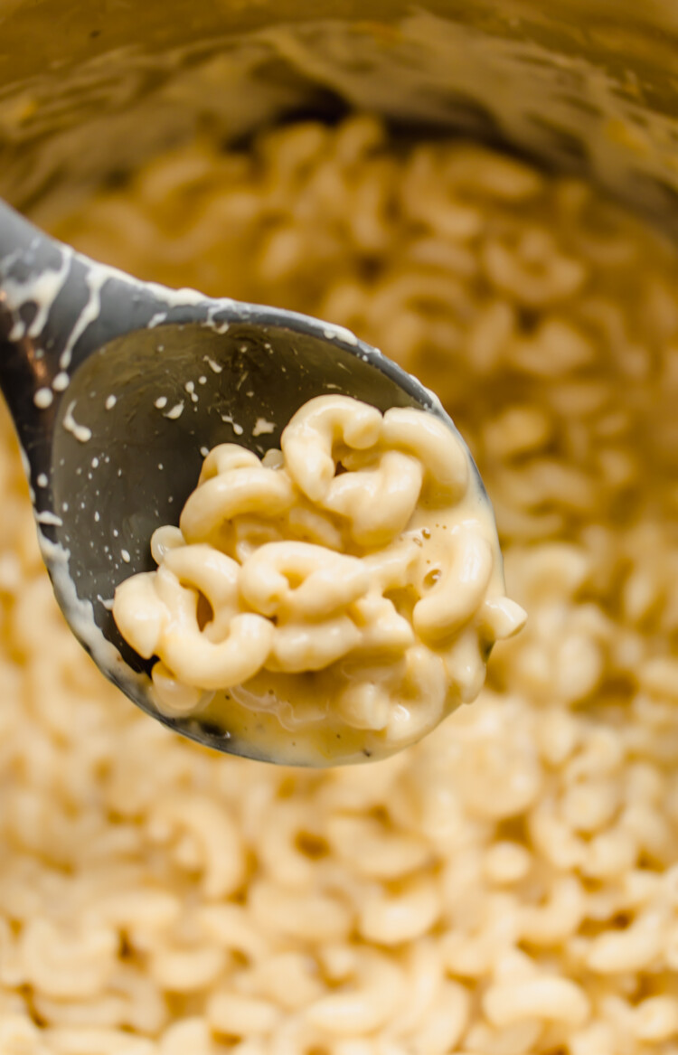 A spoon scooping mac and cheese out of a pan.