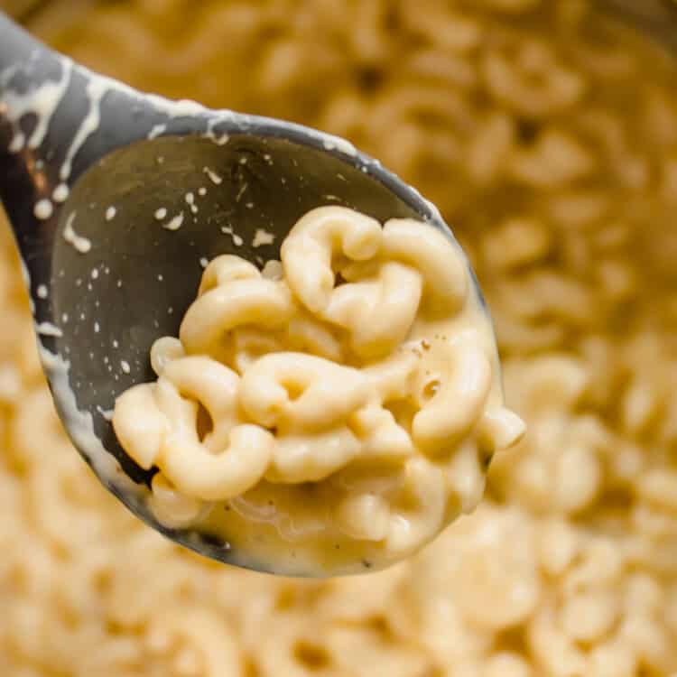 A spoon scooping mac and cheese out of a pan.