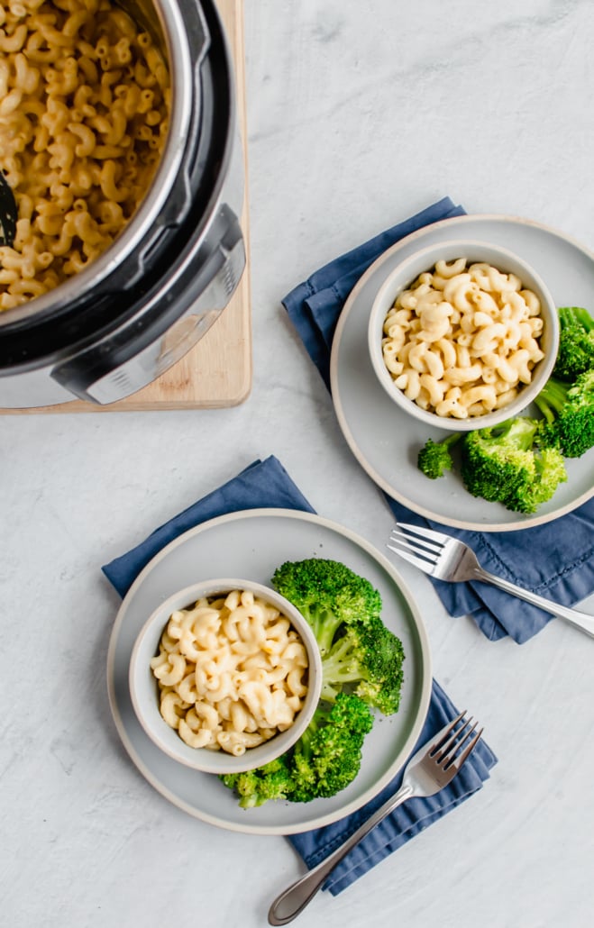 instant pot mac and cheese in bowls on white plates with steamed broccoli on the side